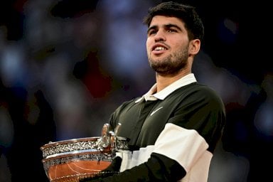 الاسباني كارلوس ألكاراس يحمل كأس بطولة رولان غاروس المتوج بها على حساب الايطالي يانيك سينر في باريس في الثامن من حزيران/يونيو 2025