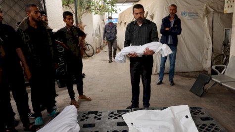 رجل يحمل جثمان طفل فلسطيني قتل في قصف اسرائيلي، أمام مشرحة مستشفى في رفح بجنوب قطاع غزة في 27 نيسان (أبريل) 2024