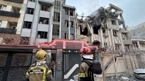 عمال إنقاذ يقفون أمام مبنى منهار بعد الهجوم الإسرائيلي