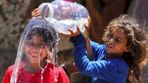 طفلة في غزة تصب الماء على رأس صديقتها