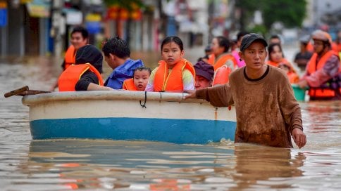 أشخاص يخوضون مياه الفيضانات في نها ترانج، مقاطعة خانه هوا، فيتنام - Shutterstock