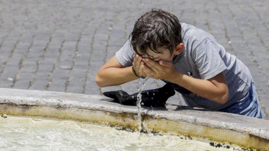 طفل يغسل وجهه بالماء في يوم حار